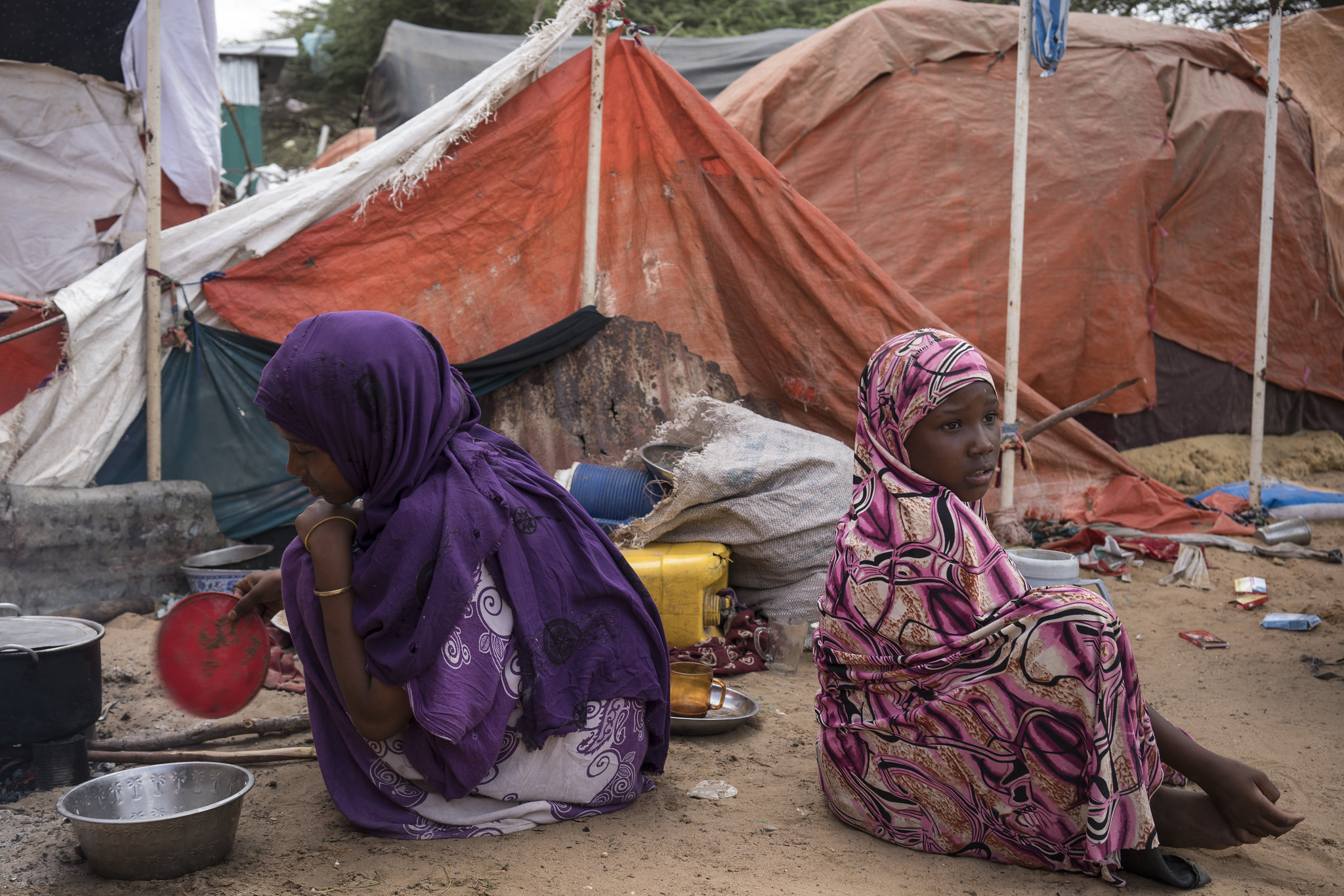 Two girls who have been displaced by the drought sit and cook by their tent in K13 IDP camp in Mogadishu, Somalia, Thursday, April 6, 2017. Credit: UNICEF/Mackenzie Knowles-Coursin