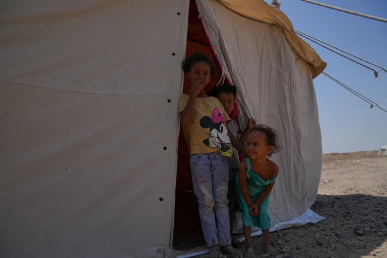 UNCIEF/2026/Yem/Mahmoud Alfilastini Children in front of their tent in AlFirdos displacement camp around Aden. Tens of thousands of children have been internally displaced after escalation in violence on the western coast of Yemen early September 2026