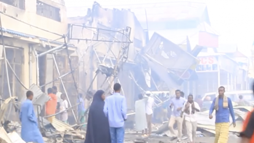 People walk through the aftermath of a devastating fire on Saturday, August 24, 2024, at Ceelasha Biyaha Market.